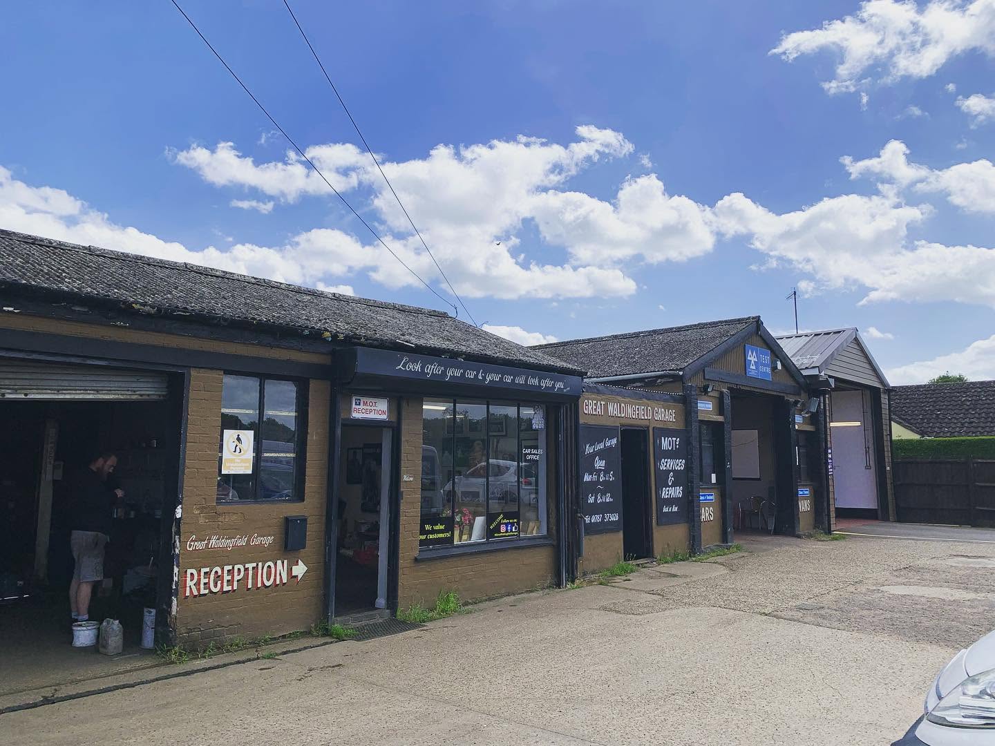 The Great Waldingfield Garage yard on the Lavenham Road: MOT reception, painted sign boards and the test centre bays